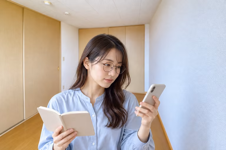 スマートフォンとノートを見比べ、候補を考える女性の横顔