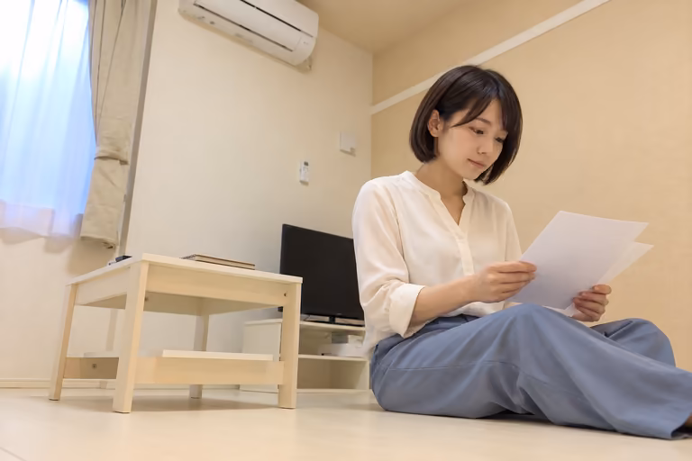 低いテーブルの横に座って書類を見比べる女性