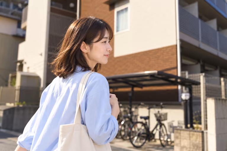 集合住宅の前を歩く女性の横顔