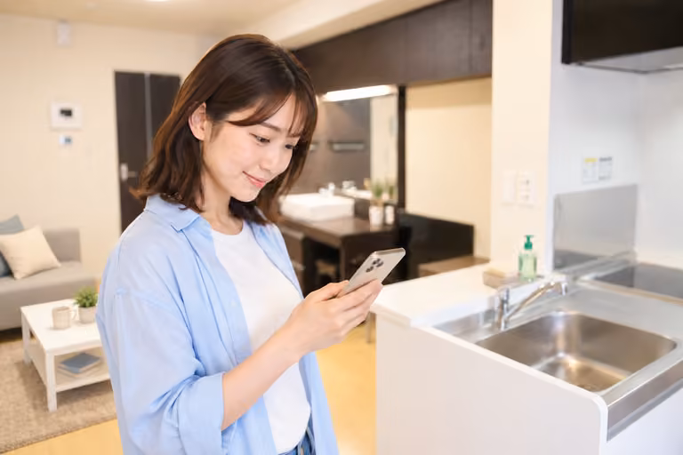 ソファやラグのある室内で、スマートフォンを見る女性